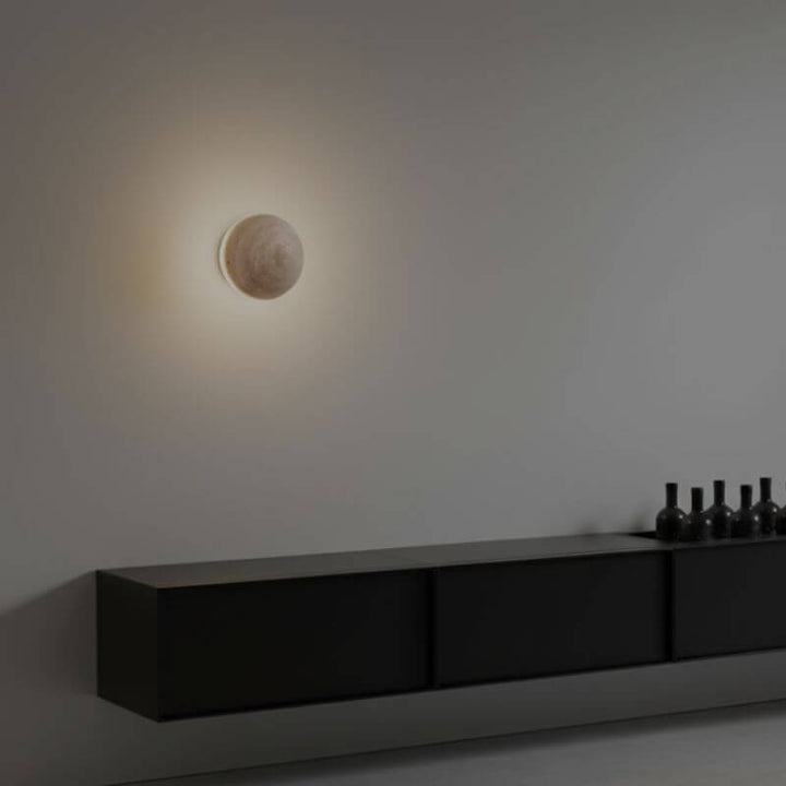 Arandela de Parede Travertino Soleil em formato esférico com luz amarelada