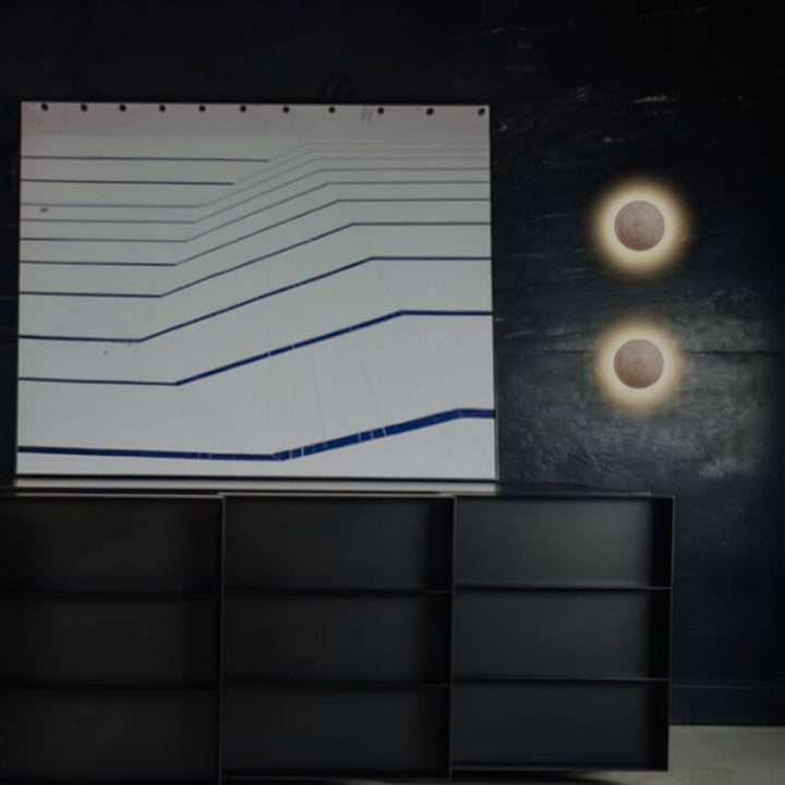 Arandela de Parede Travertino Soleil em formato esférico com luz amarelada em fundo branco profissional